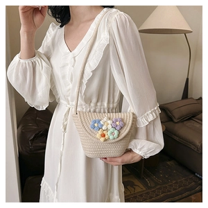Detail of beige straw crossbody bucket bag featuring colorful floral crochet decorations