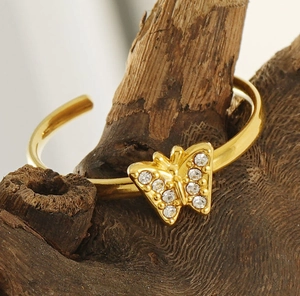 Macro shot of gold butterfly ring with inlaid zircons on a rustic wooden stand