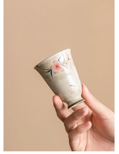 Close-up of hand-painted peach blossom ceramic teacup with high-foot green base detail