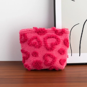 Detail of plush pink makeup bag with 3D heart texture and soft fleece material