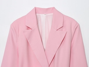 Gros plan du col d'un blazer rose, tissu lisse, doublure blanche et étiquette S