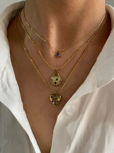 Detail of layered gold necklaces with shell, heart, and flower pendants with colorful stones