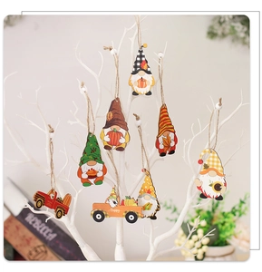 Detail of wooden gnome ornaments and pumpkin truck hanging on a white seasonal tree