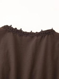 Dettaglio dell'abito marrone scuro con bordo in pizzo traforato e trama del tessuto tessuto