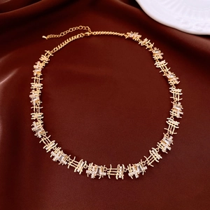 Detail of gold necklace with rectangular zircons on brown satin background