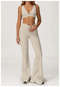 Vista frontale set yoga beige con reggiseno sportivo a V e pantaloni svasati a vita alta