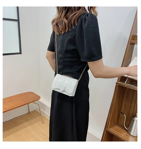 Detail of white quilted heart-shaped mini chain bag worn as an elegant crossbody accessory