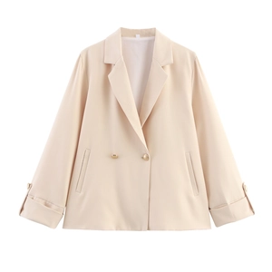 Detail of apricot blazer featuring classic lapels and decorative golden buttons