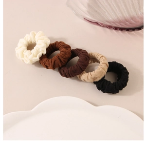 Detail of five earth-toned ribbed knit hair scrunchies in minimalist neutral colors