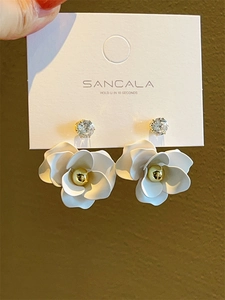 Macro shot of white camellia flower earrings with cubic zirconia on display card