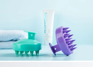 Detailed view of teal and purple silicone scalp massagers with soft cleaning bristles