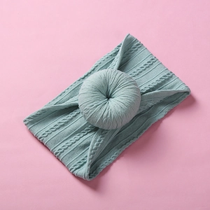 Detailed close-up of light teal nylon baby headband with knitted donut knot texture