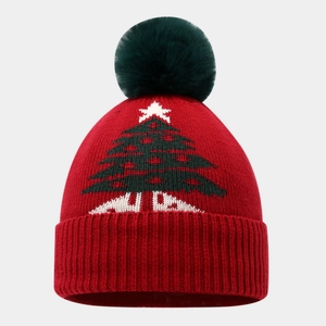 Detail einer roten Strickmütze mit grünem Weihnachtsbaummuster und flauschigem Bommel