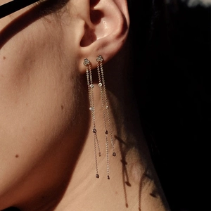 Close-up of elegant gold long tassel earrings with sparkling white crystals on model
