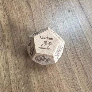 Detailed engraving of food options like Chicken and Pasta on the wooden decision dice
