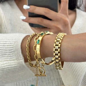 Set aus 18k vergoldeten Edelstahlarmbändern mit grünem Zirkon an einem Frauenhandgelenk