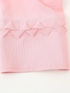 Detail of pink chiffon fabric showing geometric triangle patchwork and texture on the sleeve