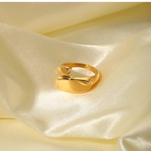 Close-up of golden geometric 18k gold-plated ring on smooth yellow silk background