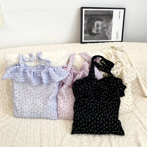 Detail of four floral tote bags featuring ruffle edges and adjustable straps on plush surface