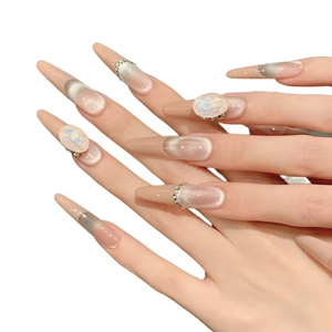 Faux ongles faits main amande nude avec effet œil de chat et strass de luxe