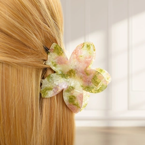 Detailed macro view of a pink and green spotted floral hair claw clip on blonde hair