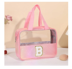 Dettaglio della trousse olografica rosa con grande patch B glitterata e manico robusto