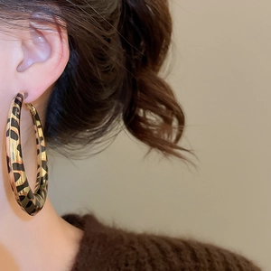 Close-up of model wearing large leopard print hoop earrings with retro aesthetic