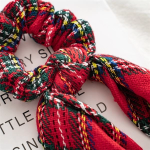 Detailed close-up of red tartan velvet scrunchie with festive bow for Christmas hair styling