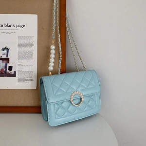 Close-up of light blue quilted leather bag with pearl buckle and decorative pearl strap
