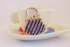 Macro detail of handbag-shaped keychain with black and white rhinestones on golden frame
