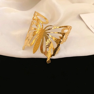 Detailed view of large golden butterfly cuff bracelet with hollow wings and hammered texture