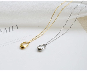 Detailed close-up of polished gold and silver hollow teardrop pendants on a card
