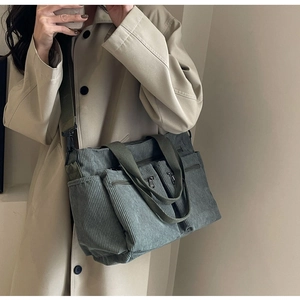 Detail of corduroy tote bag in grey-green with zipper pockets and adjustable strap