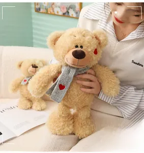 Primer plano de un suave oso de peluche con bufanda de corazón en un ambiente acogedor
