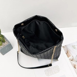 Black woven vertical texture tote bag with gold chain strap and spacious interior