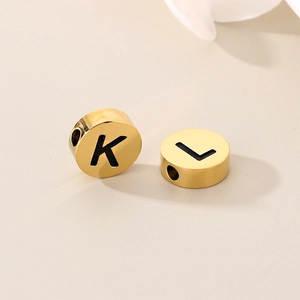 Macro shot of gold stainless steel alphabet beads showing black letters K and L details
