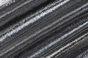 Detailed macro view of black metallic fabric with silver glitter texture and pleats