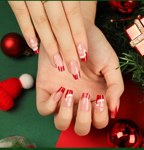 Detail of Christmas press-on nails with red Santa hat designs and HO HO festive patterns