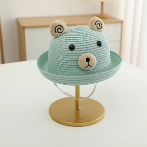 Détail d'un chapeau de paille vert clair pour enfant avec oreilles d'ours et cordon élastique