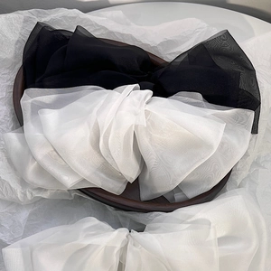 Detail of oversized black and white layered organza bow hair clips on wood tray