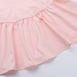 Détail de la robe rose montrant l'ourlet à volants et la texture du tissu uni