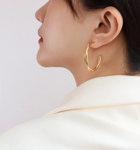 Close-up of elegant double-layered twisted hoop earrings in 18k gold finish on model