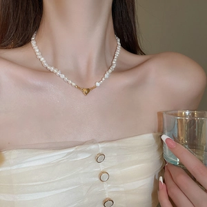 Elegant 18K gold heart pendant with freshwater pearl necklace worn by a model