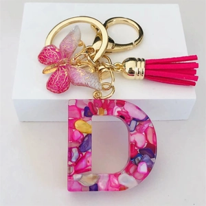 Detail of resin letter D keychain with pink butterfly charm and silk tassel accessory