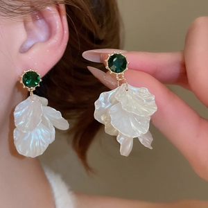 Detail of petal drop earrings with green stones and pearl luster finish on a model