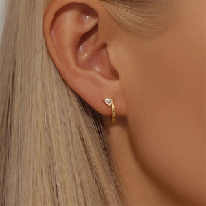 Macro shot of gold S925 sterling silver hoop earring with water drop cubic zirconia