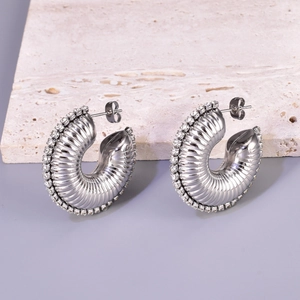 Detailed macro view of textured silver steel C-hoop earrings with small clear stones
