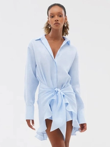 Detail of light blue shirt dress featuring waist knot and ruffled asymmetrical hemline