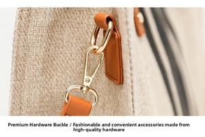 Detailed close-up of golden metal swivel hook and brown leather trim on canvas bag