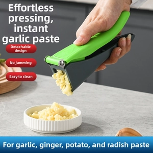 Macro detail of the manual garlic press featuring a dual-tone green and grey handle design
